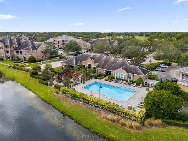 community pool featuring a water view, a residential view, and a patio