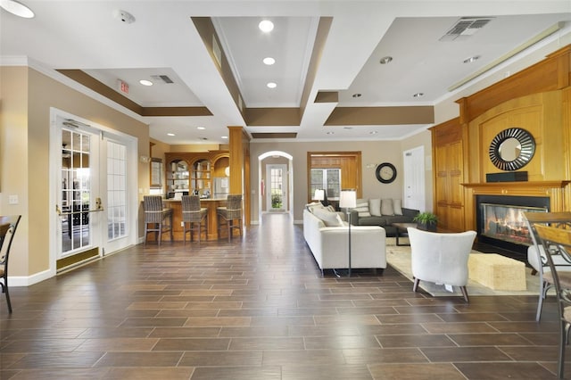 living area featuring ornamental molding, a glass covered fireplace, french doors, and visible vents