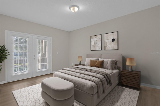 bedroom featuring access to exterior, french doors, baseboards, and wood finished floors