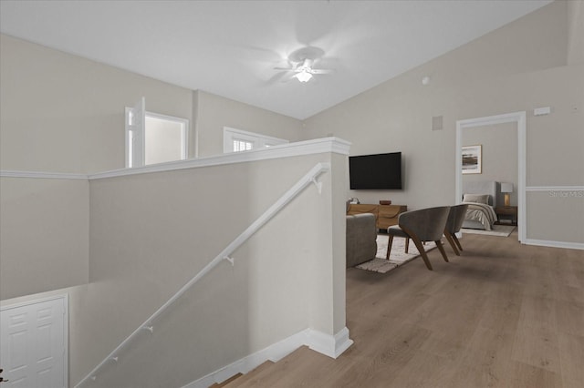 hallway with vaulted ceiling, wood finished floors, an upstairs landing, and baseboards