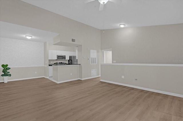 unfurnished living room featuring baseboards, visible vents, and light wood finished floors