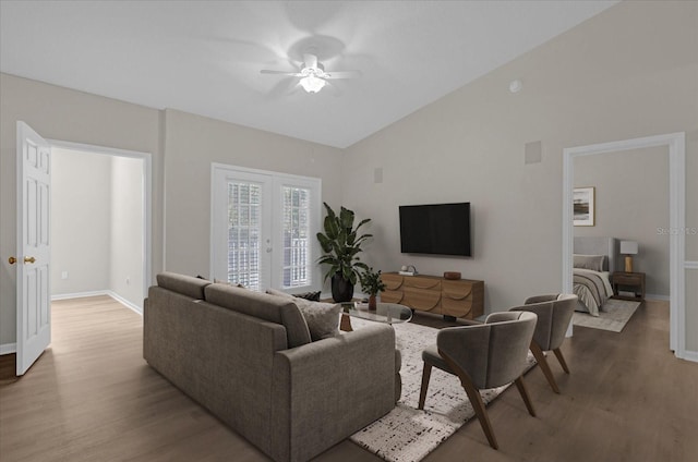 living area featuring vaulted ceiling, french doors, wood finished floors, and baseboards