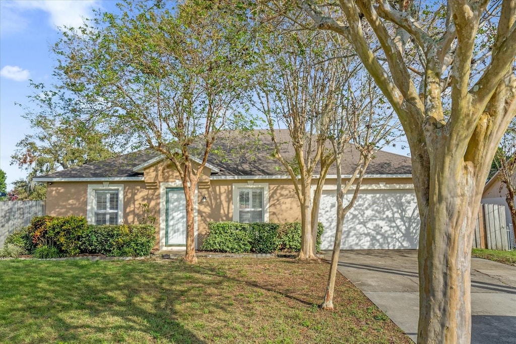 ranch-style home featuring a garage and a front lawn