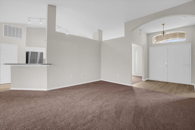 foyer featuring lofted ceiling, light carpet, and track lighting