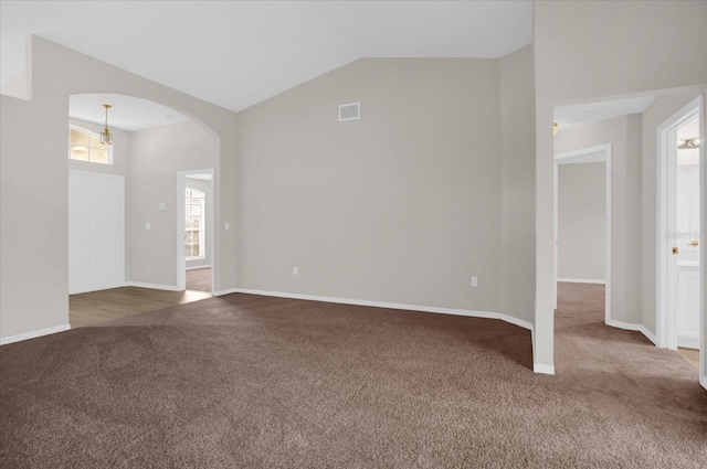 carpeted empty room with vaulted ceiling