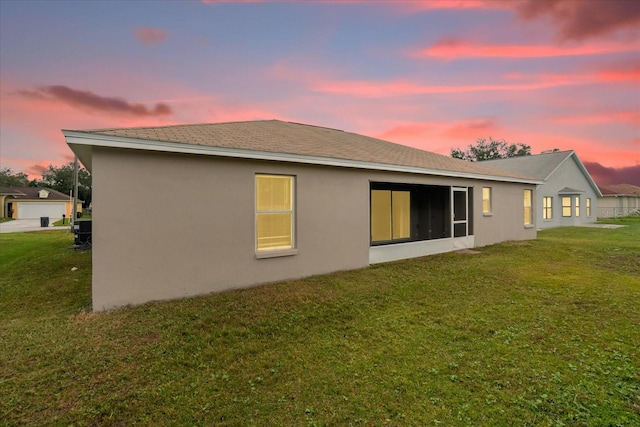 back house at dusk with a lawn