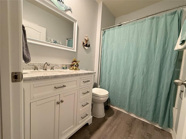 bathroom featuring walk in shower, wood-type flooring, toilet, and vanity