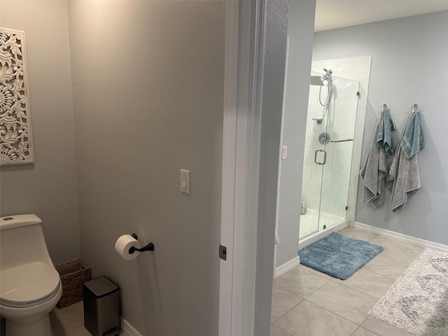 bathroom with toilet, tile patterned floors, and a shower with shower door