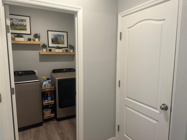 clothes washing area with washing machine and clothes dryer and dark hardwood / wood-style floors