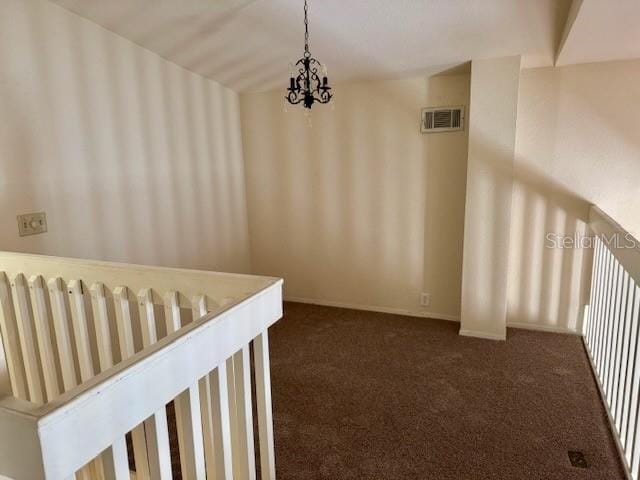 corridor with a chandelier and dark carpet