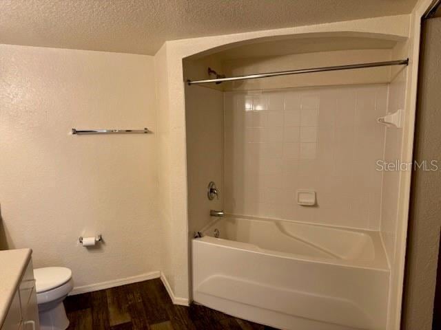 full bathroom featuring tub / shower combination, hardwood / wood-style floors, a textured ceiling, toilet, and vanity