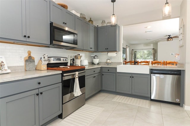 kitchen featuring stainless steel appliances, ceiling fan, sink, gray cabinets, and hanging light fixtures