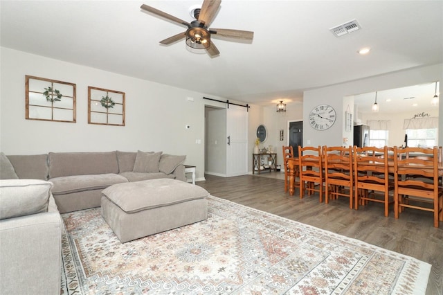 living room with a barn door, ceiling fan, and hardwood / wood-style floors