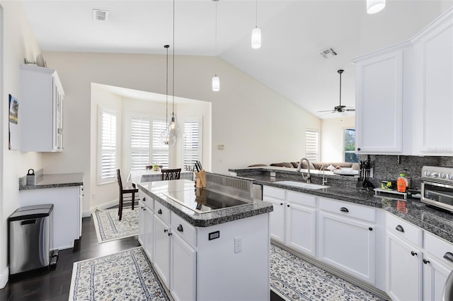 kitchen with a wealth of natural light, sink, stovetop, white cabinetry, and lofted ceiling