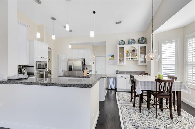 kitchen featuring stainless steel appliances, dark hardwood / wood-style floors, kitchen peninsula, pendant lighting, and white cabinets