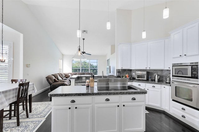 kitchen featuring white cabinets, appliances with stainless steel finishes, high vaulted ceiling, and hanging light fixtures