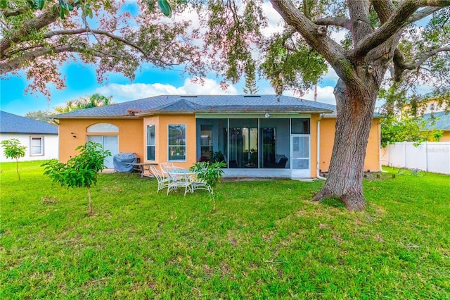 back of property with a lawn and a sunroom