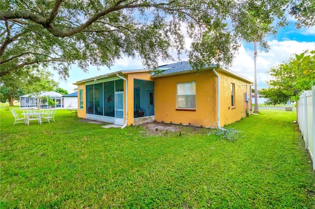 back of house with a lawn and a sunroom