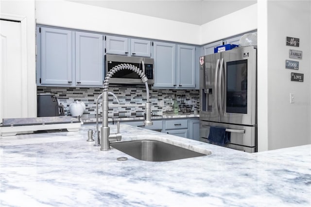 kitchen featuring light stone counters, sink, stainless steel appliances, and tasteful backsplash