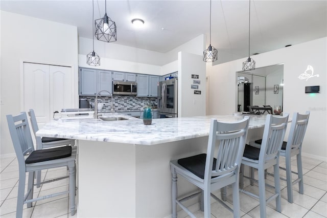 kitchen featuring light tile patterned floors, stainless steel appliances, hanging light fixtures, and a breakfast bar area