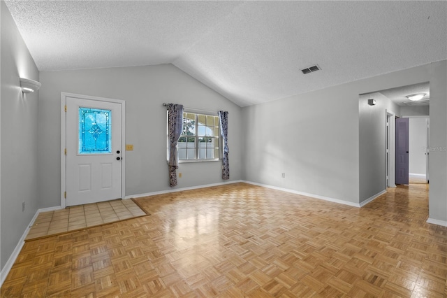 entrance foyer with a textured ceiling, light parquet floors, and vaulted ceiling