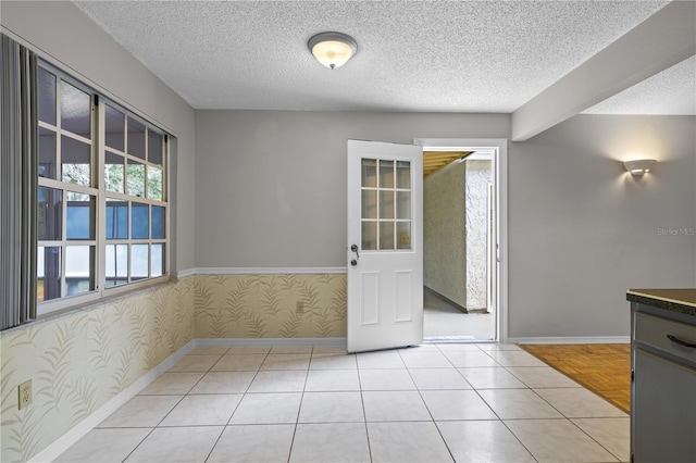 interior space with light tile patterned flooring, beamed ceiling, and a textured ceiling