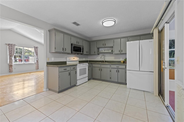 kitchen with sink, a textured ceiling, white appliances, lofted ceiling, and gray cabinetry