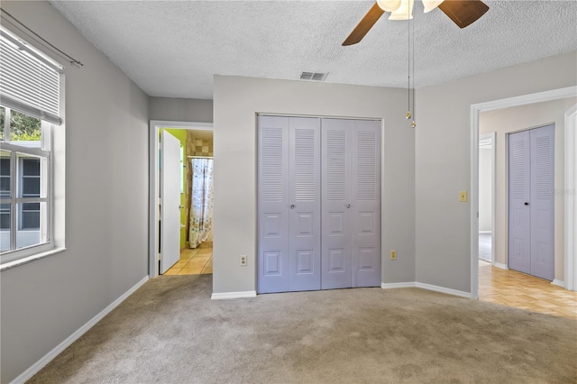 unfurnished bedroom featuring a textured ceiling, light colored carpet, and ceiling fan