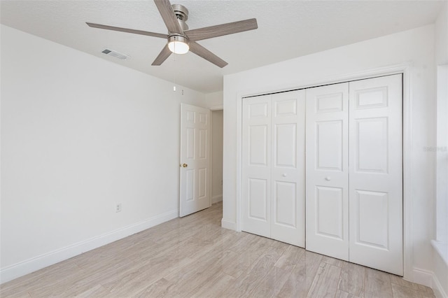 unfurnished bedroom with ceiling fan, a closet, a textured ceiling, and light wood-type flooring