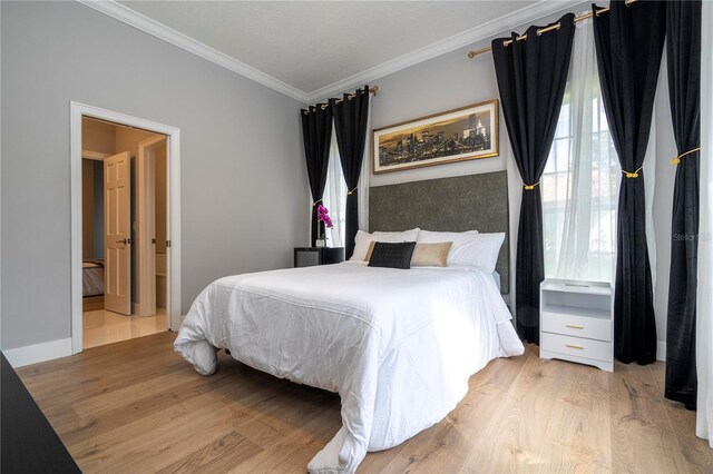 bedroom with crown molding, ensuite bathroom, and light wood-type flooring