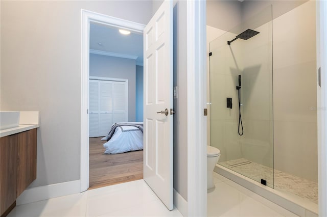 bathroom featuring tiled shower, hardwood / wood-style flooring, toilet, and ornamental molding