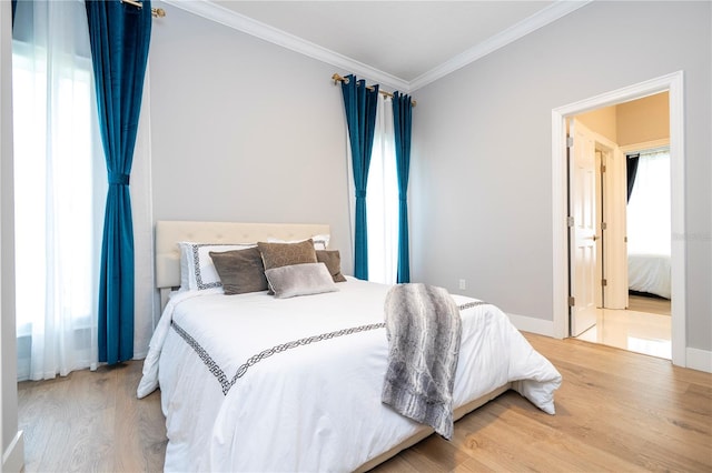 bedroom featuring light hardwood / wood-style floors, crown molding, and multiple windows