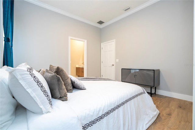 bedroom featuring connected bathroom, ornamental molding, and light wood-type flooring