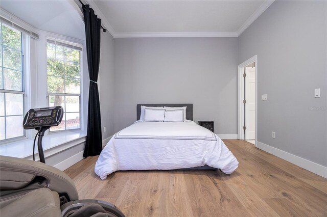 bedroom featuring hardwood / wood-style floors, multiple windows, and ornamental molding