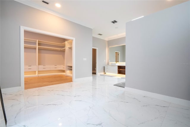 bedroom with a walk in closet, crown molding, and a closet