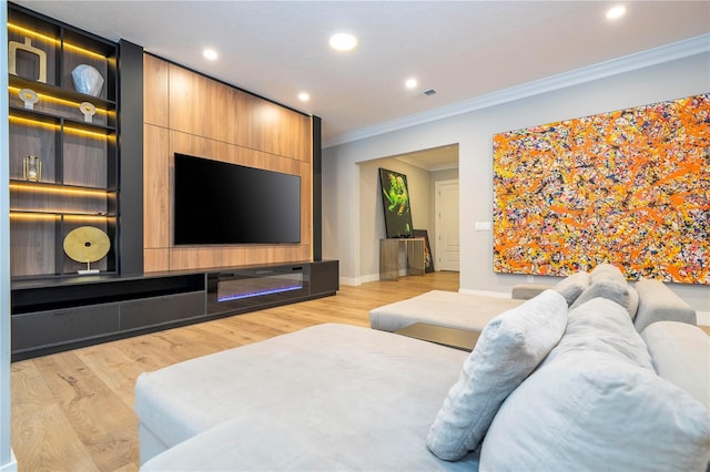 home theater room with ornamental molding and light hardwood / wood-style flooring