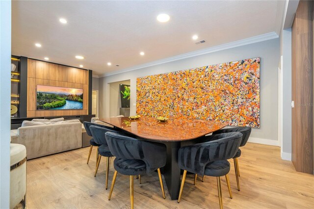 dining space with light hardwood / wood-style floors and ornamental molding