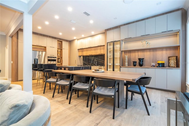 dining space with light hardwood / wood-style floors and crown molding