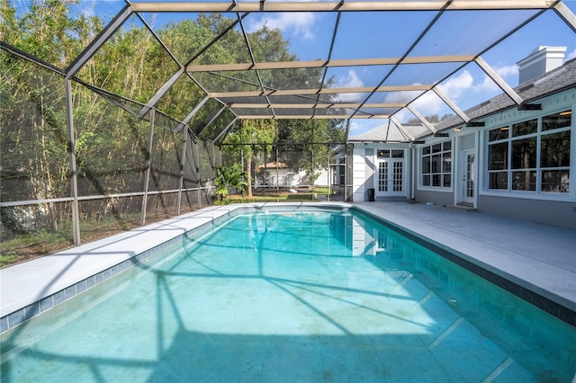 view of swimming pool featuring glass enclosure, a patio area, and french doors