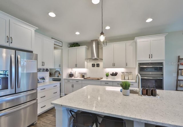 kitchen featuring wall chimney exhaust hood, white cabinetry, and appliances with stainless steel finishes