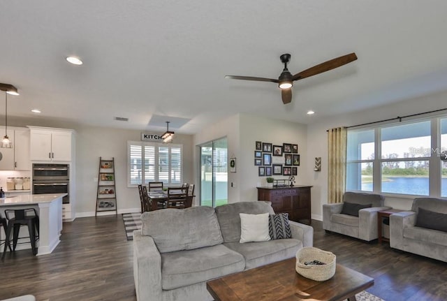 living room with dark wood-type flooring and ceiling fan