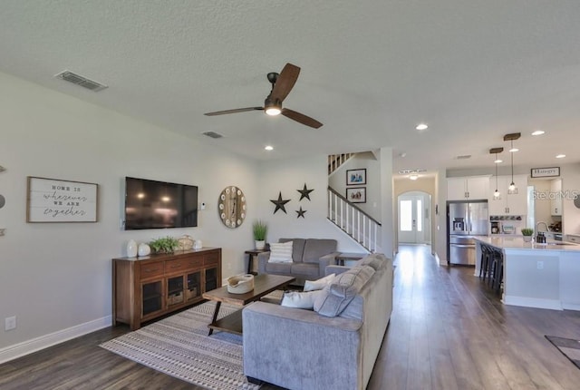 living room with a textured ceiling, dark hardwood / wood-style flooring, ceiling fan, and sink