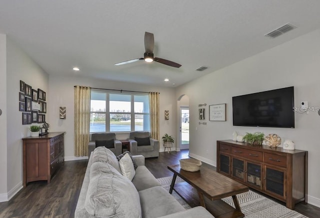 living room featuring dark wood-type flooring and ceiling fan