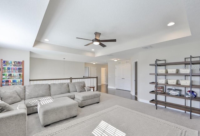 living room featuring ceiling fan and a raised ceiling