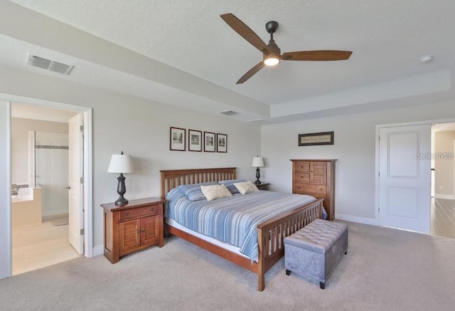 bedroom featuring connected bathroom, a textured ceiling, light carpet, and ceiling fan