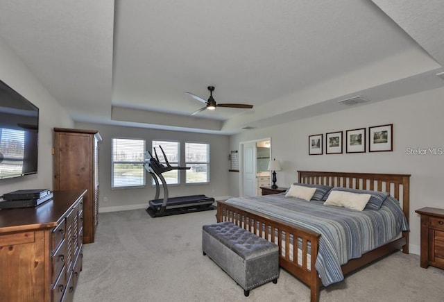 carpeted bedroom with ceiling fan and a raised ceiling