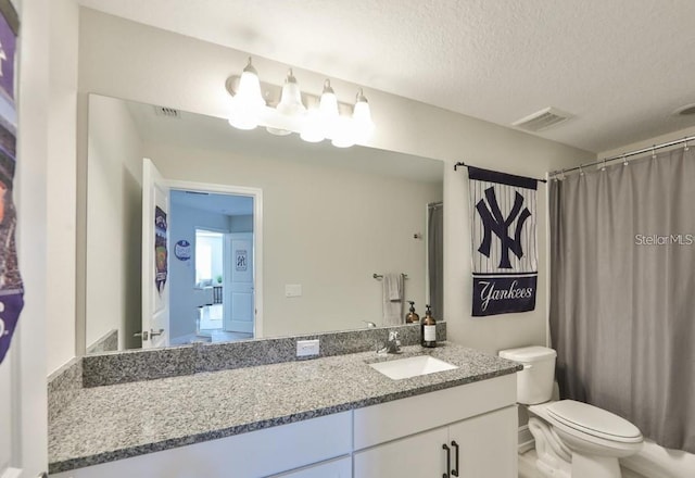 bathroom with vanity, a textured ceiling, and toilet