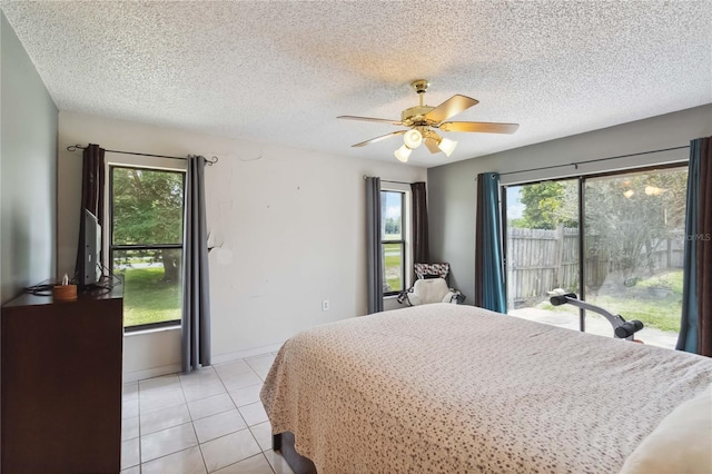 bedroom with multiple windows, light tile patterned floors, a textured ceiling, and ceiling fan