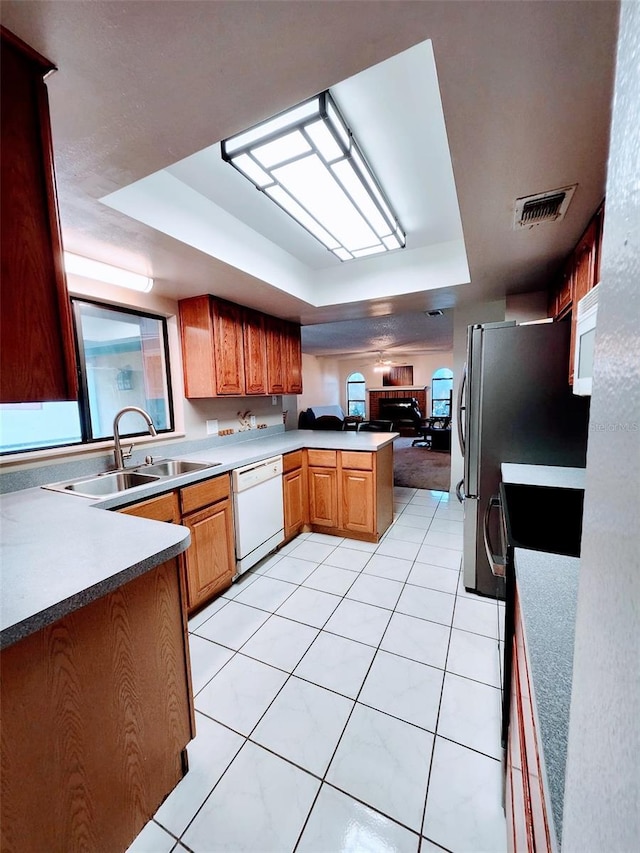 kitchen with kitchen peninsula, sink, white dishwasher, a tray ceiling, and black electric range