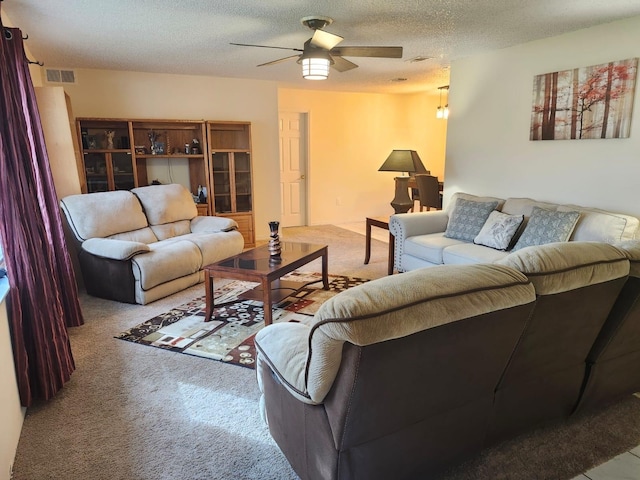 carpeted living room featuring ceiling fan and a textured ceiling